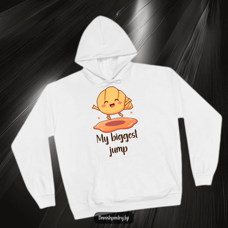 Funny hoodie depicting a happy croissant with legs mid-air, leaping over a jam puddle. Cozy and humorous pastry apparel.