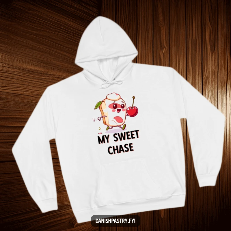 Funny Danish pastry hoodie, character comically chasing a rolling cherry, cozy and humorous apparel.