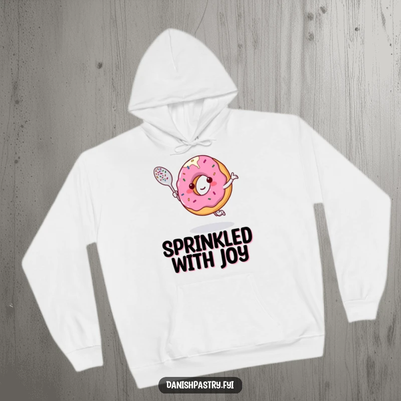 Funny hoodie featuring a smiling donut character dancing with a sprinkle-covered spoon, offering warmth and sugary delight.