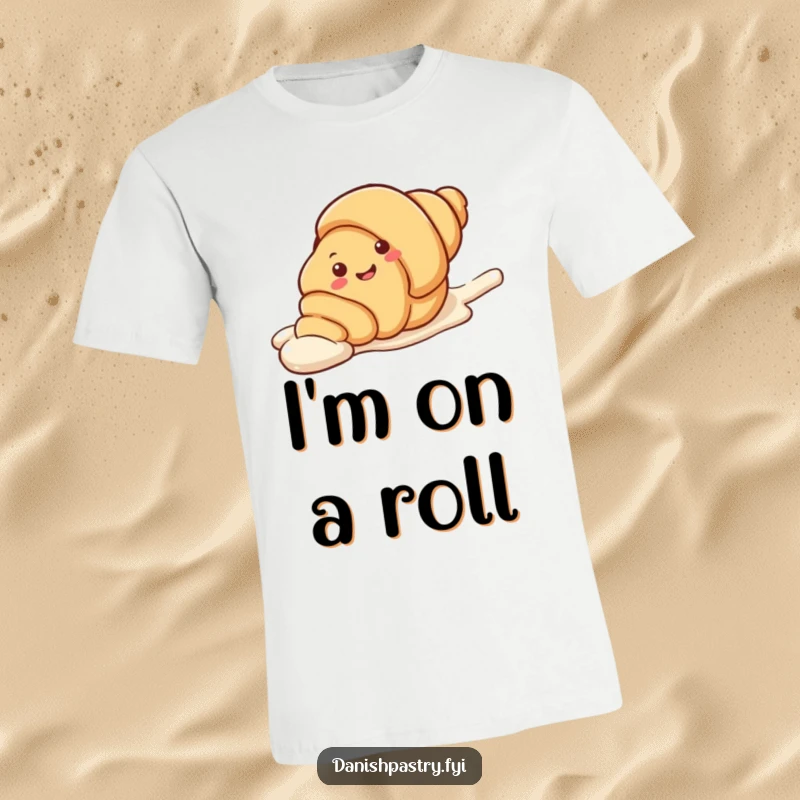 Funny T-Shirt depicting a smiling croissant character sliding playfully on a streak of white icing. A humorous and sweet graphic tee.